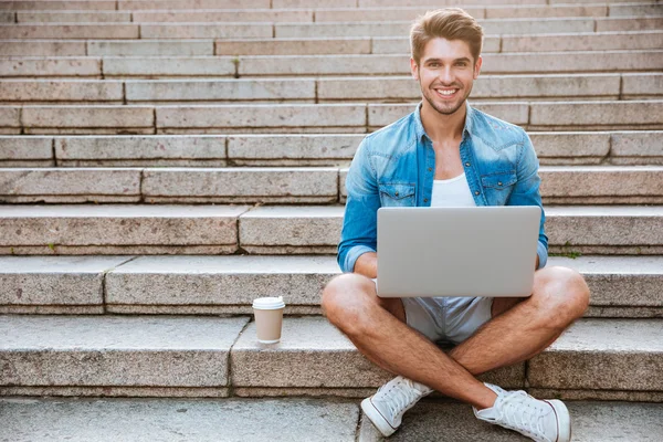 Mann benutzt Laptop, während er im Treppenhaus sitzt — Stockfoto