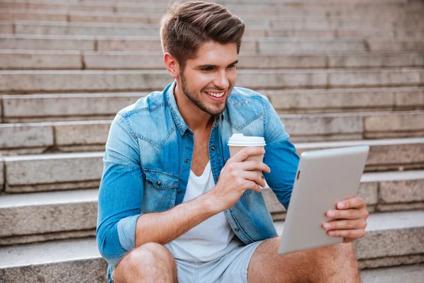 Sonriendo hombre casual feliz usando PC tableta y beber café — Foto de Stock