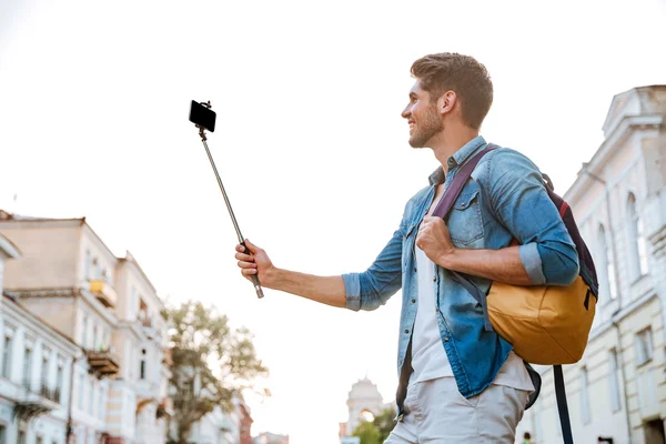 Toerist met rugzak maken van selfies geïsoleerd op prachtige moderne gebouwen — Stockfoto