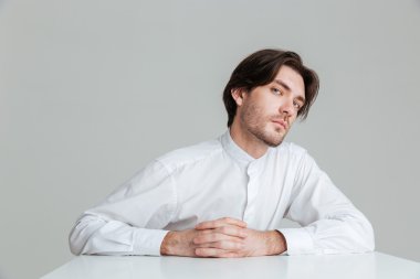 Masada oturan beyaz gömlekli konsantre genç adam