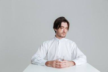 Masada otururken su bardağı tutan adam