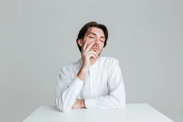 Hombre con los ojos cerrados pensando en algo en la mesa —  Fotos de Stock