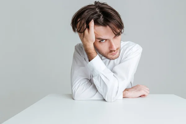 Pensive man in wit overhemd zittend aan de tafel — Stockfoto