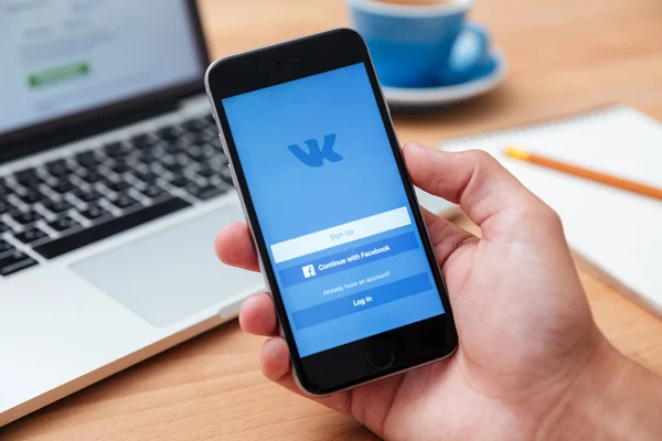 Mężczyzna, trzymając iphone 6 wyświetlone Vkontakte aplikacji — Zdjęcie stockowe