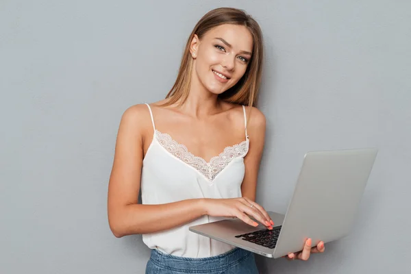 Sorrindo menina bonito usando laptop e olhando para a câmera — Fotografia de Stock