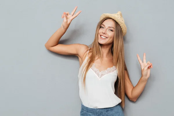 Portret van een lachende vrouw in hoed vredesteken tonen — Stockfoto