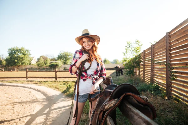 Cheerful smiling cowgirl preparing horse saddle for a ride — Stock Photo, Image