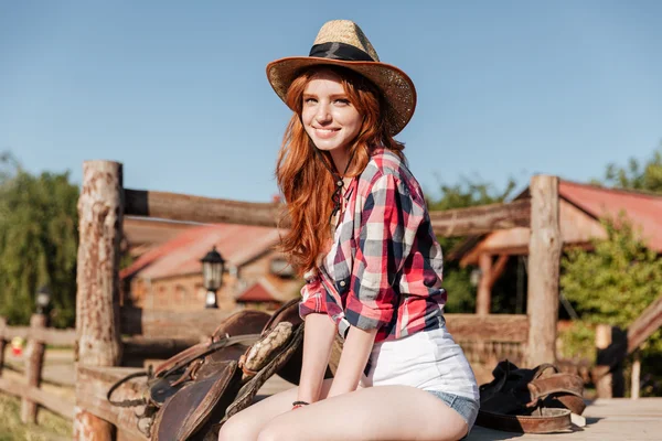 Roztomilá zrzka cowgirl sedí a položenou na ranč plot — Stock fotografie