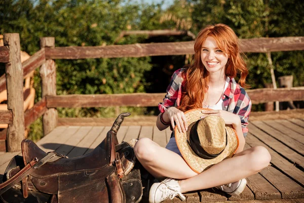 Szczęśliwa kobieta cowgirl kapeluszu siedzi na ranczo — Zdjęcie stockowe