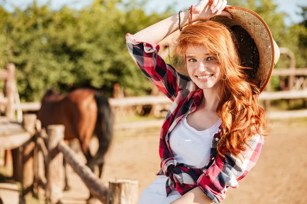 Szczęśliwa kobieta cowgirl siedzi i uśmiecha się na ranczo — Zdjęcie stockowe