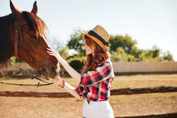 Donna sorridente cowgirl prendersi cura del suo cavallo in fattoria — Foto Stock