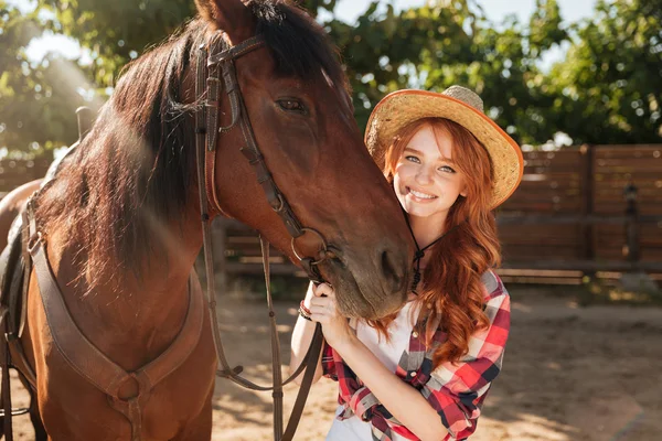 Vrolijke vrouw cowgirl in hoed met haar paard in dorp — Stockfoto