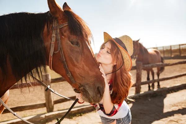Niedliche Frau Cowgirl stehend und küsst ihr Pferd — Stockfoto