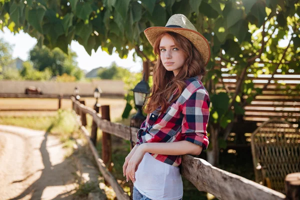 Porträt eines hübschen rothaarigen Cowgirls, das sich auf den Ranchzaun lehnt — Stockfoto