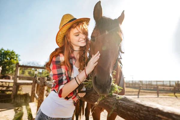 Lachende vrouw cowgirl verzorgen en knuffelen haar paard — Stockfoto