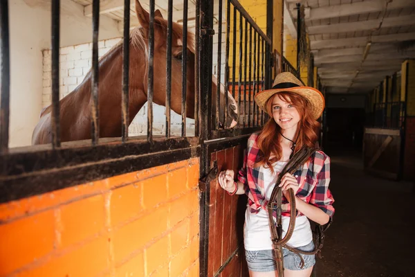 Wesoła kobieta cowgirl z konia stoi w stajni — Zdjęcie stockowe