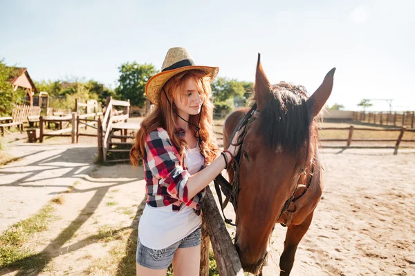 Mooie vrouw cowgirl het verzorgen van haar paard op de boerderij — Stockfoto