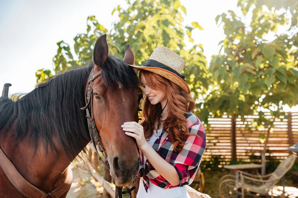 快乐的年轻女子女牛仔站在牧场与她的马 — 图库照片
