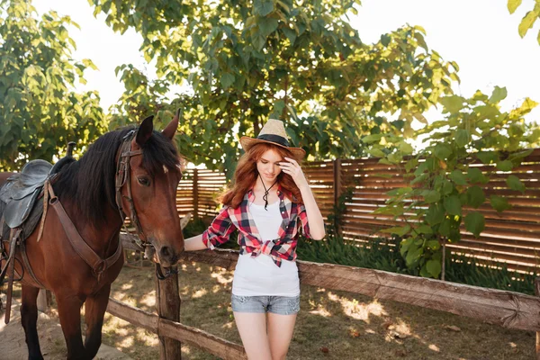 Donna cowgirl a piedi con il suo cavallo nel villaggio — Foto Stock