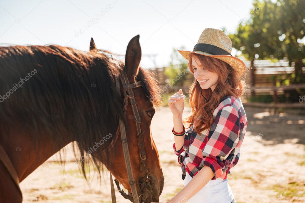 Cute lovely cowgirl taking care of her horse on ranch
