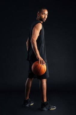 Omzunun üzerinden bakarak konsantre bir basketbolcu yan görünüm