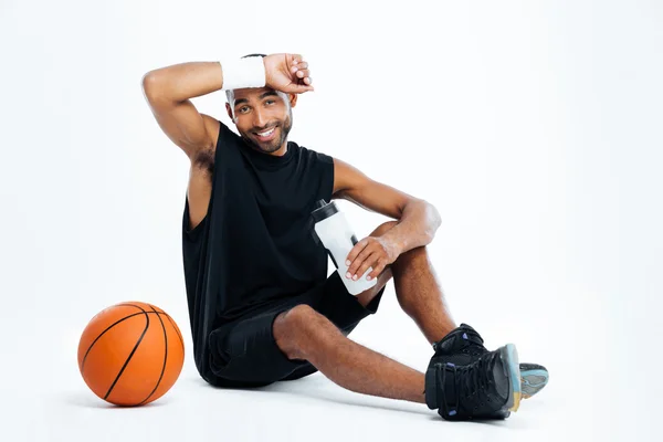 Cansado joven jugador de baloncesto sentado y beber agua — Foto de Stock