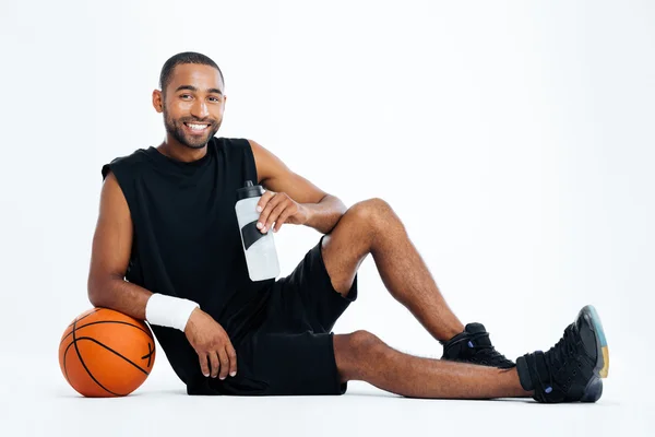 Cheerful young man basketball player sitting and drinking water — Stock Photo, Image