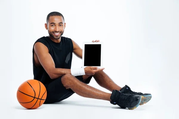 Hombre feliz jugador de baloncesto sentado y sosteniendo la tableta de pantalla en blanco — Foto de Stock