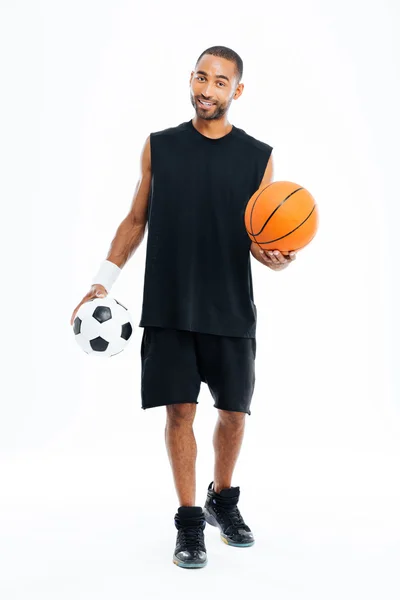 Sonriente africano deportista sosteniendo pelota de baloncesto y fútbol — Foto de Stock