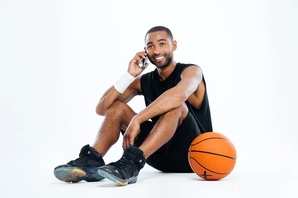 Hombre feliz jugador de baloncesto sentado y hablando en el teléfono celular — Foto de Stock