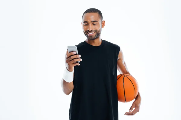 Smiling young sportsman standing and listening to music from smartphone — Stock Photo, Image