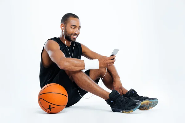 Fröhlicher junger Mann Basketballspieler sitzt und Musik hört — Stockfoto