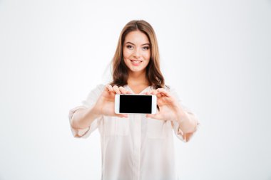 Boş akıllı telefon ekranı gösteren gülümseyen neşeli bir kadın portresi