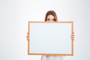 Young woman with eyes wide open peeping from blank board