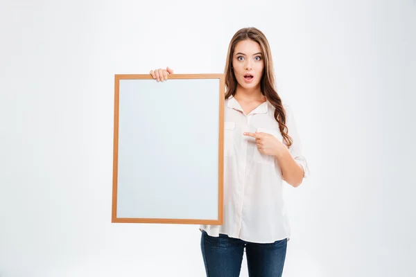 Portret van een lachende vrouw wijzend vinger op blanco bord — Stockfoto