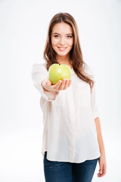 Cheerful young woman giving apple at camera — Stock Photo, Image