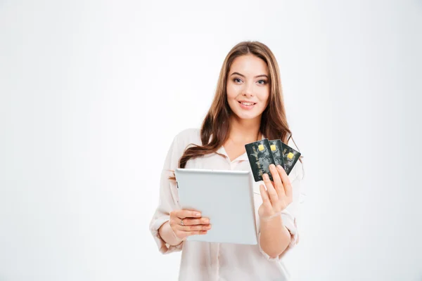 Smiling young woman holding bank card and tablet computer