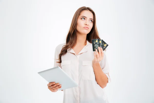 Donna pensierosa in possesso di carta di credito e utilizzando tablet computer — Foto Stock
