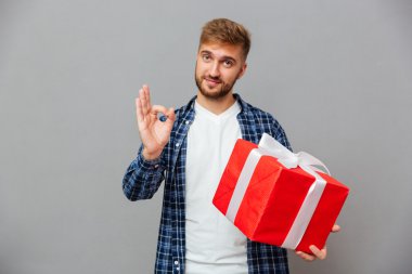 Mutlu sakallı adam hediye kutusu tutan ve ok jest gösteren