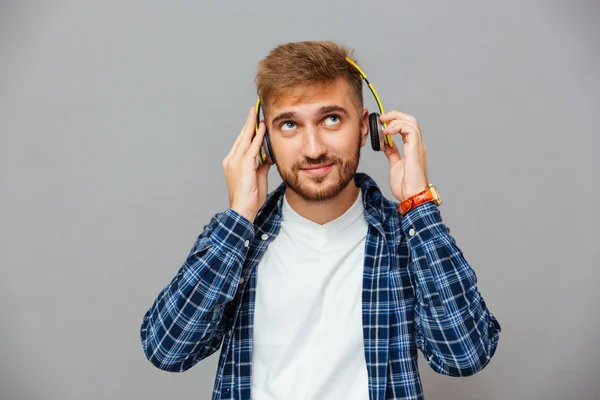 Relaxed thoughtful young man listening to music using headphones — Stockfoto