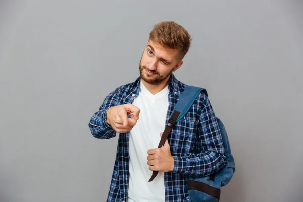 Mann mit Rucksack zeigt mit dem Finger auf Kamera und zwinkert — Stockfoto