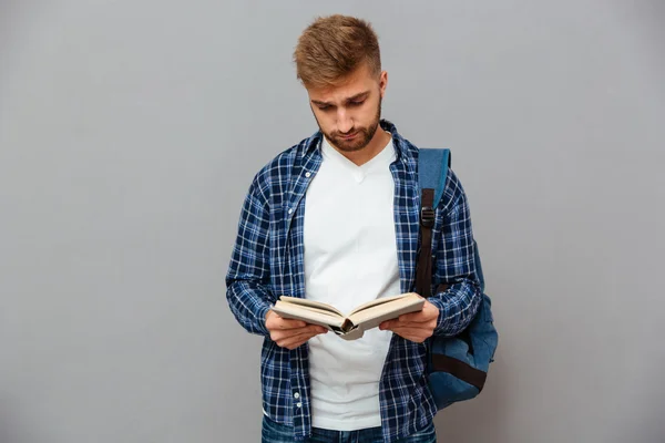 Hombre barbudo guapo con camisa a cuadros con libro de lectura de mochila — Foto de Stock