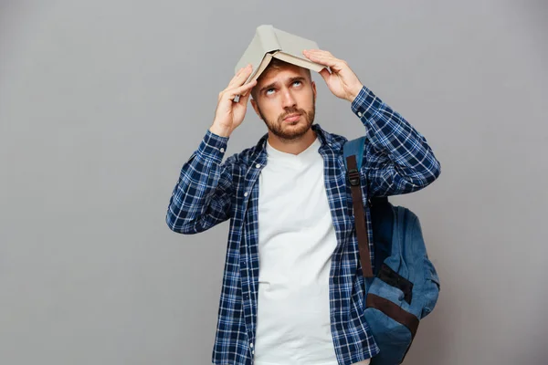 Young bearded male student with open book on his head — Stockfoto