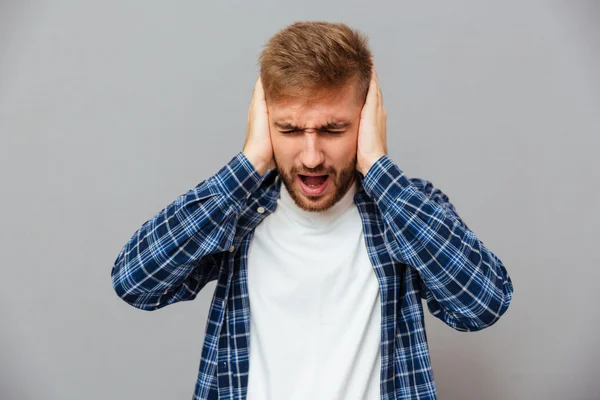 Příležitostný vousatý muž zakrývající uši a křik — Stock fotografie