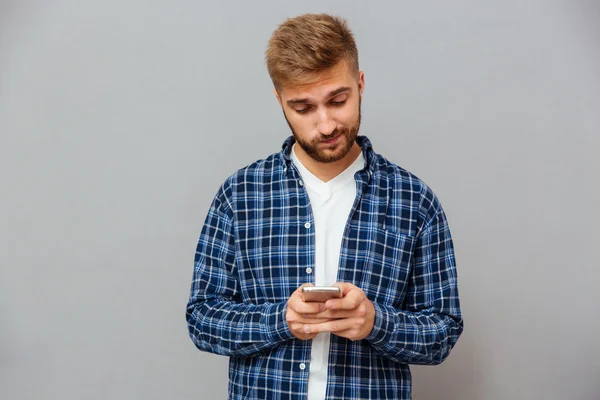 Upprörd skäggiga man textning meddelande på smartphone — Stockfoto