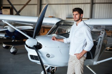 Küçük uçağın yanında duran ciddi adam