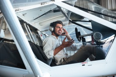 Pilot küçük uçakta oturuyor ve kulaklık kullanarak konuşan adam