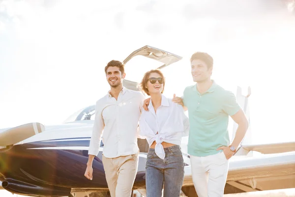 Amigos alegres caminando y abrazándose en la pista en el aeropuerto — Foto de Stock