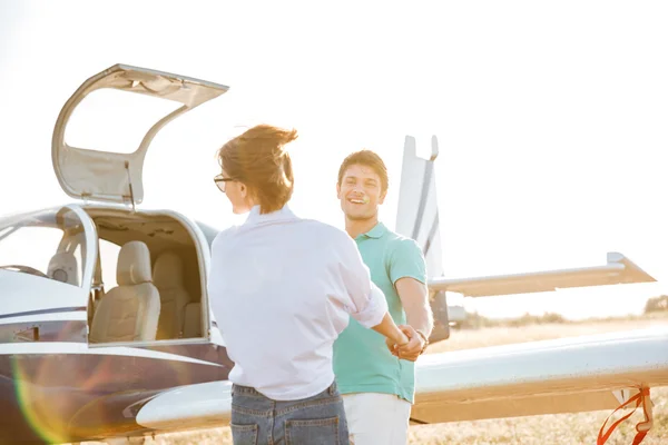 Coppia che si tiene per mano e divertirsi sulla pista vicino aereo — Foto Stock