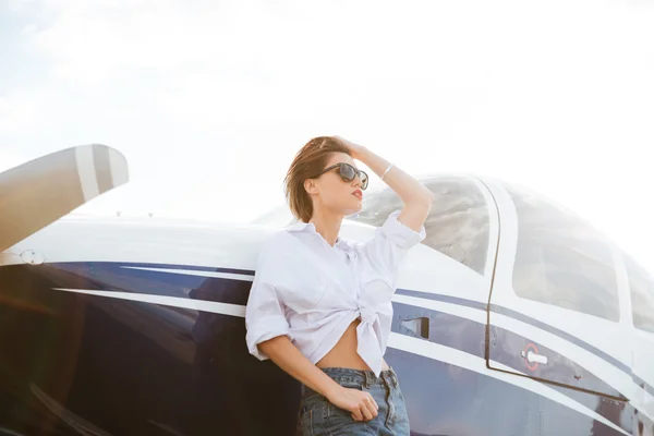 Kobieta w okulary, stojący na zewnątrz w pobliżu mały prywatny samolot — Zdjęcie stockowe